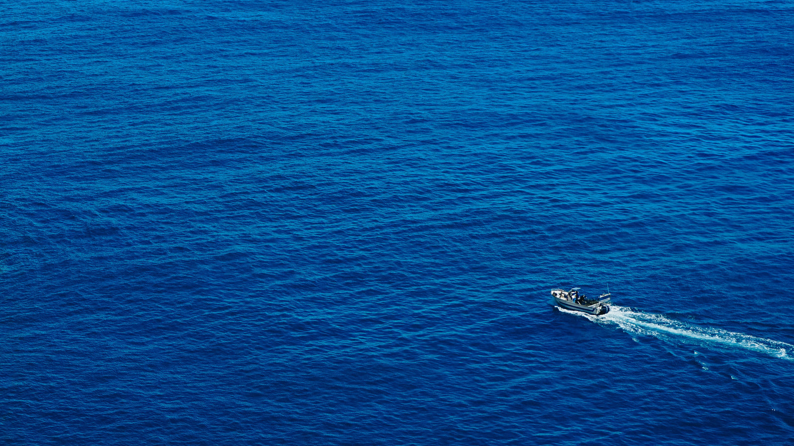 Man fishing off a boat in the distance